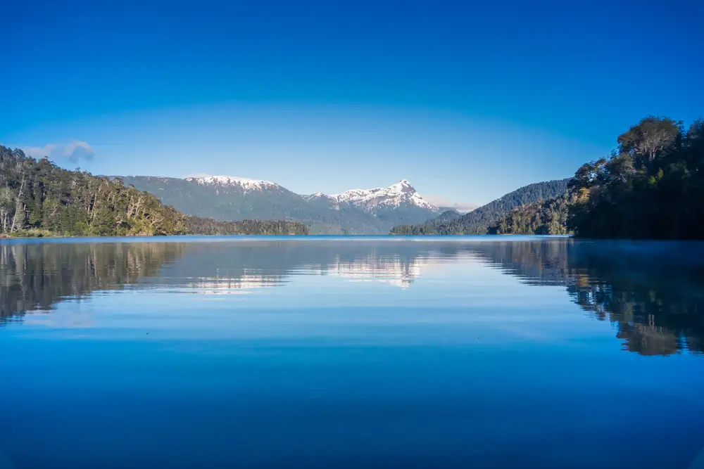 A still lake with the snow peaks reflected in it