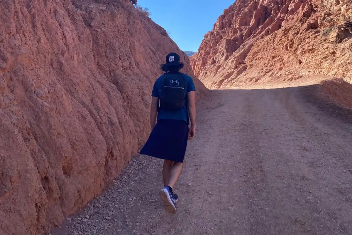 A walker on a gravel path between red rock walls