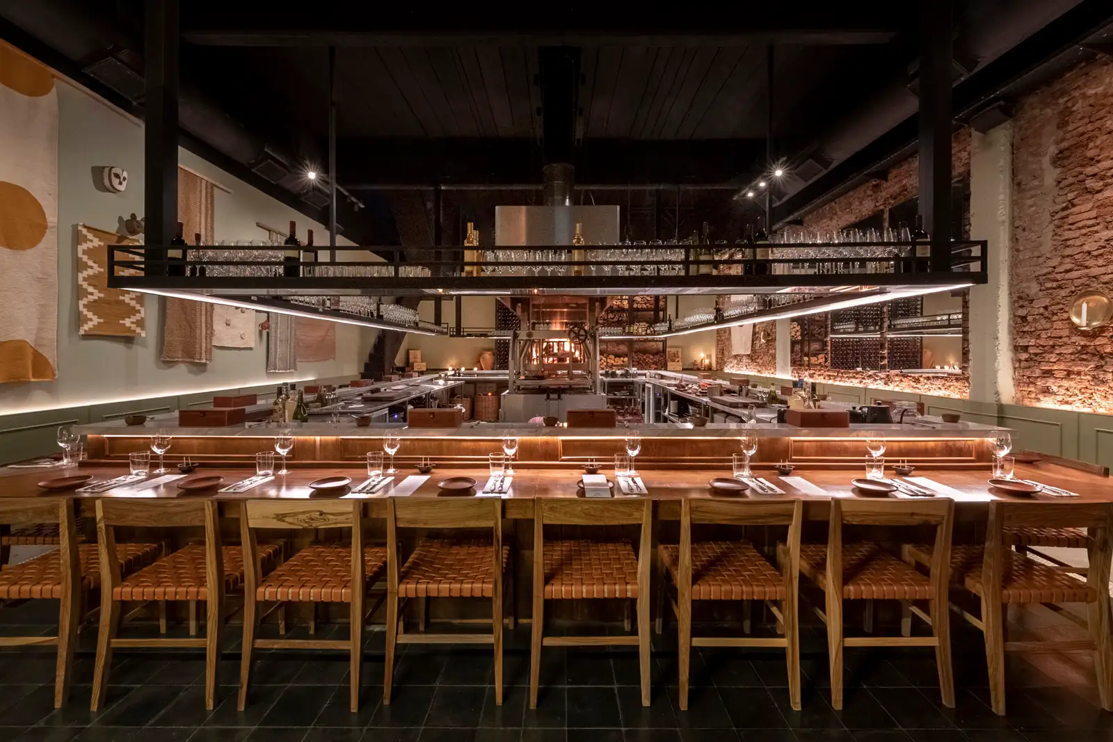 The long counter of a dark dining room, set with stools