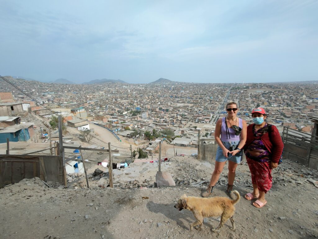 Panoramic view of lima's shanty town with local lady, tourist and a dog